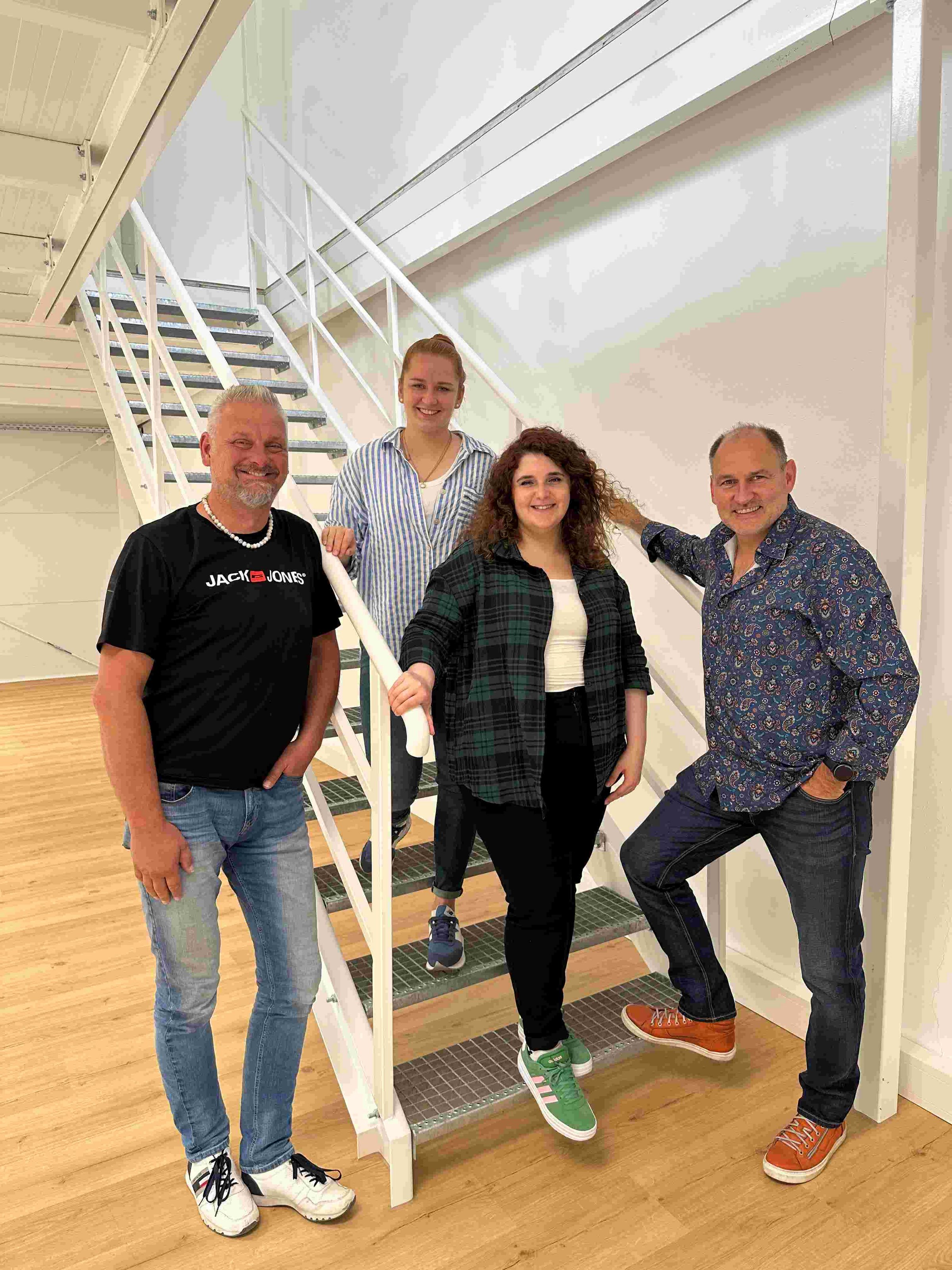 Vier Personen stehen auf Treppe und lachen ins Bild