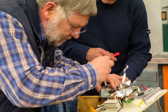 Ein Mann schaut sehr konzentriert während er etwas repariert Ein Mann schaut sehr konzentriert während er etwas repariert