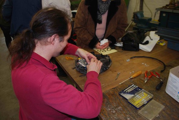 Hier sehen wir einen Teilnehmer*innen der in einer Werkstatt etwas repariert 