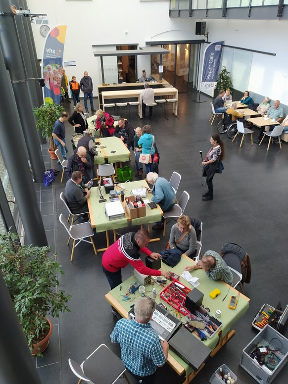 Blick von oben auf die Arbeiter im Repair Café Blick von oben auf die Arbeiter im Repair Café