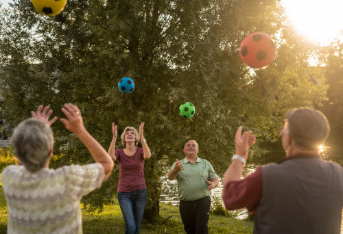 Seniorinnen und Senioren spielen sich Bälle zu in einem Park